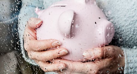 Woman with piggy bank at rainy window